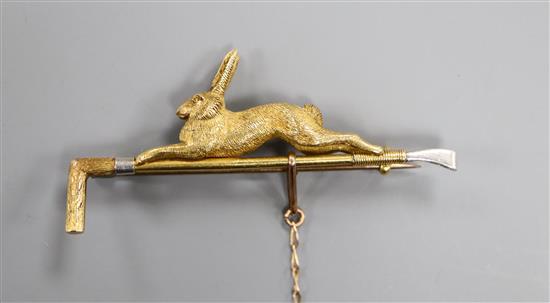 A yellow and white metal stock pin modelled as a riding crop surmounted by a running hare (tests as 18ct gold and platinum), 52mm.